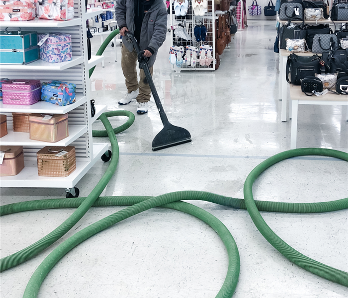 SERVPRO technician using water extraction equipment on a water-damaged carpet.